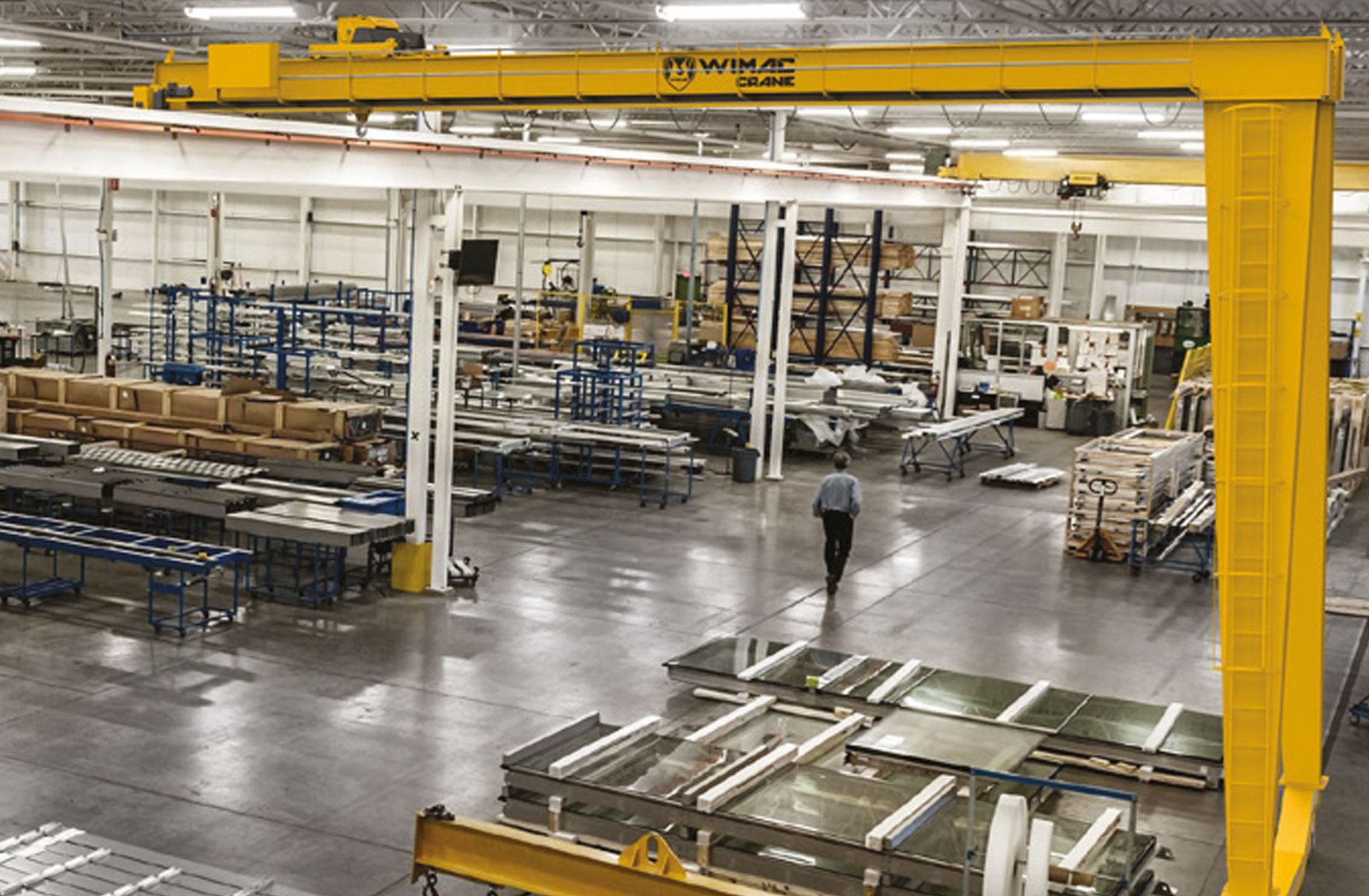 Semi gantry crane with a floor-standing leg at one end and a wall-mounted rail at the other